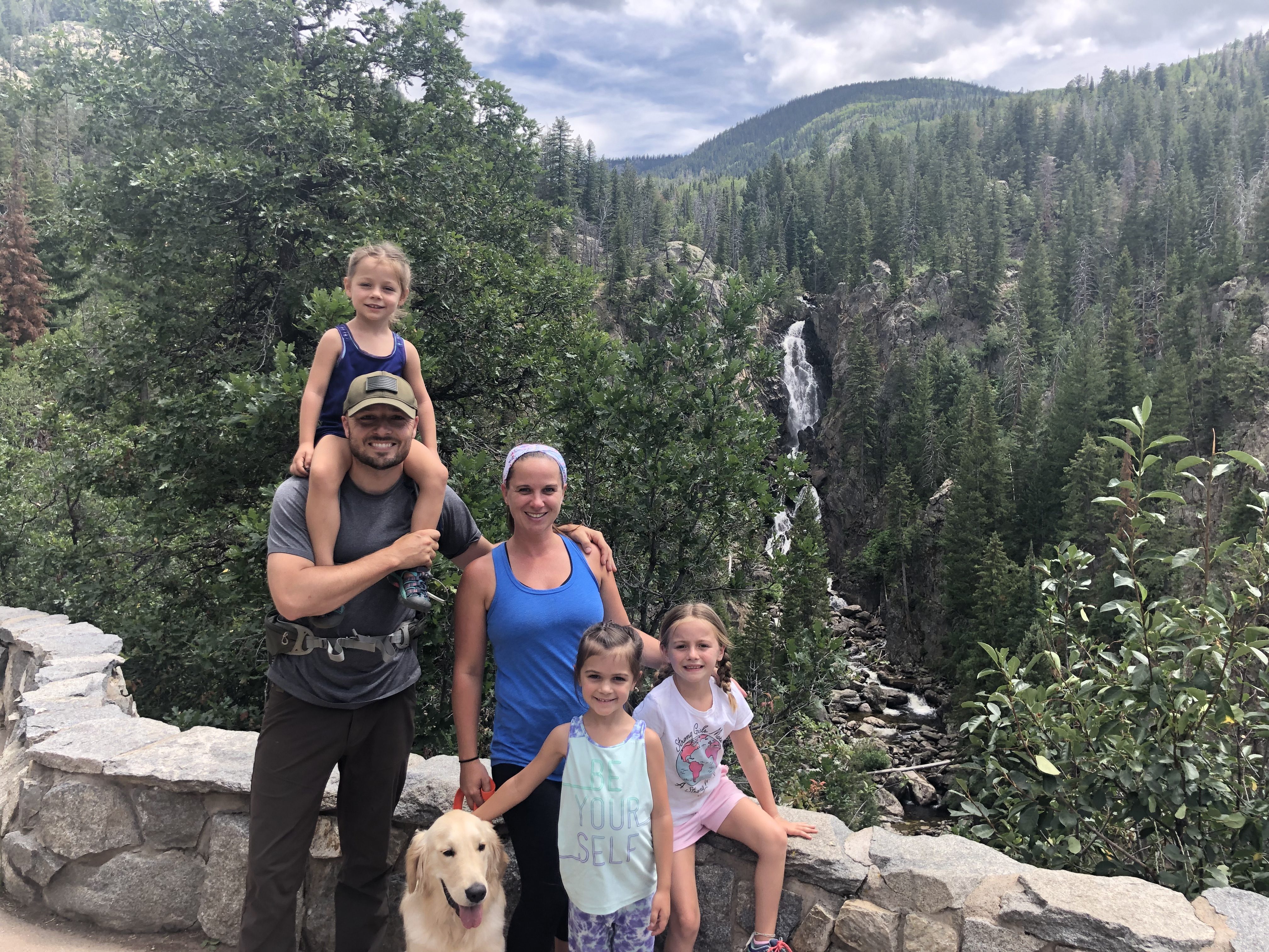 Brown family, mom, dad, 3 little girls, Golden retreiver in front of waterfall. Building resilience in children by creating outdoor adventures