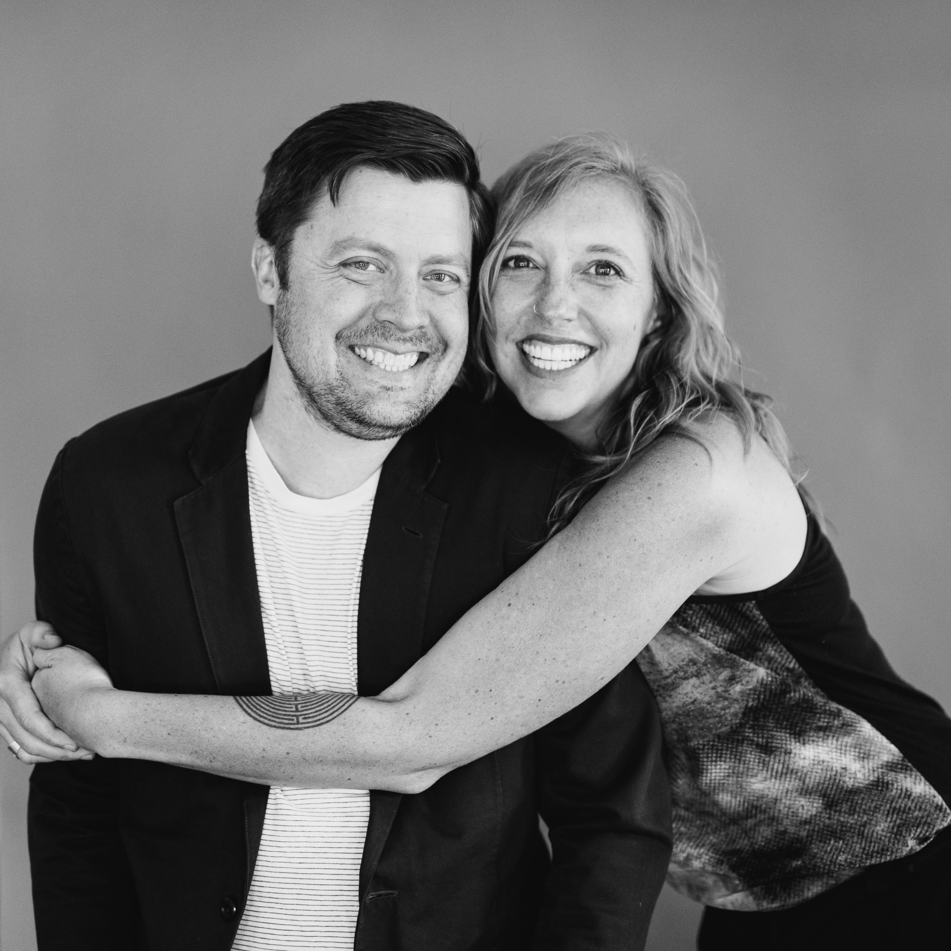 smiling couple in their early 30's, caucasian, both smiling broadly, taken in black & white. entrepreneur marriage